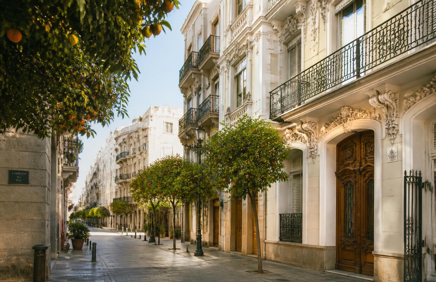 Calle soleada de Valencia con naranjos y fachadas modernistas